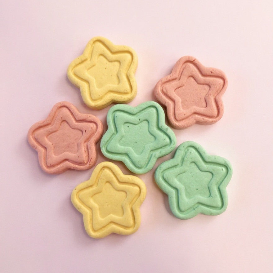 Star-shaped cookies in pastel colors on a pink background